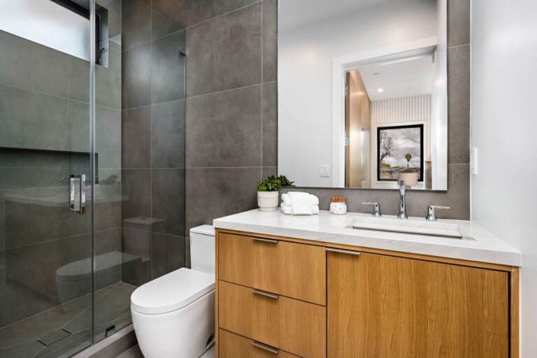 Remodeled bathroom with walk-in glass shower and wood vanity