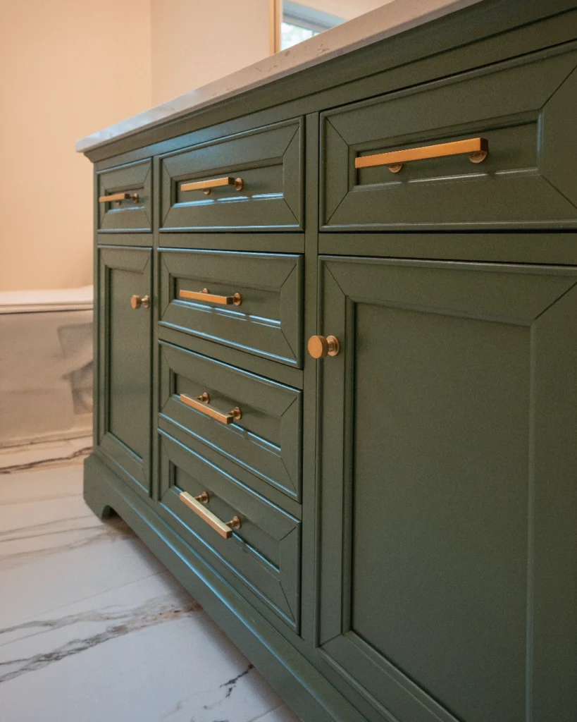 Green double vanity with brass hardware over marble floor