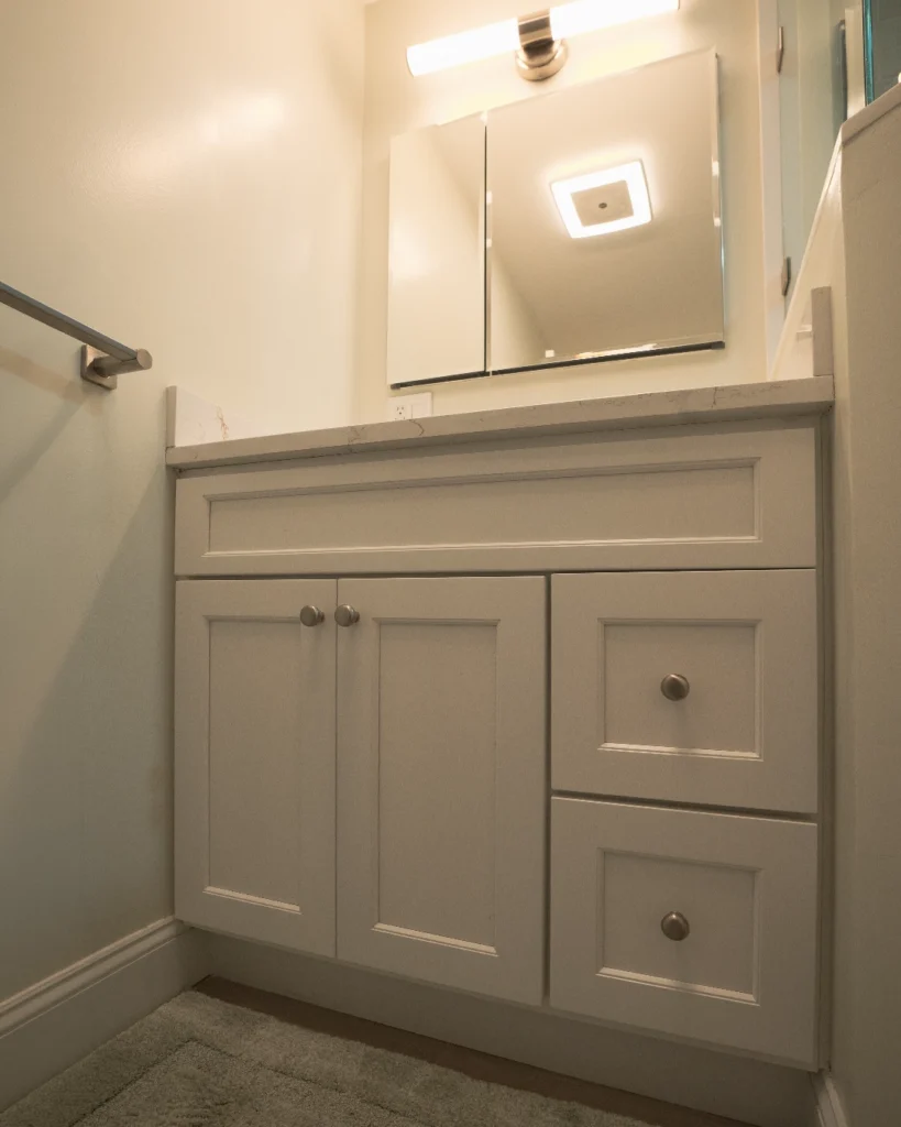 White vanity with medicine cabinet in a compact bathroom