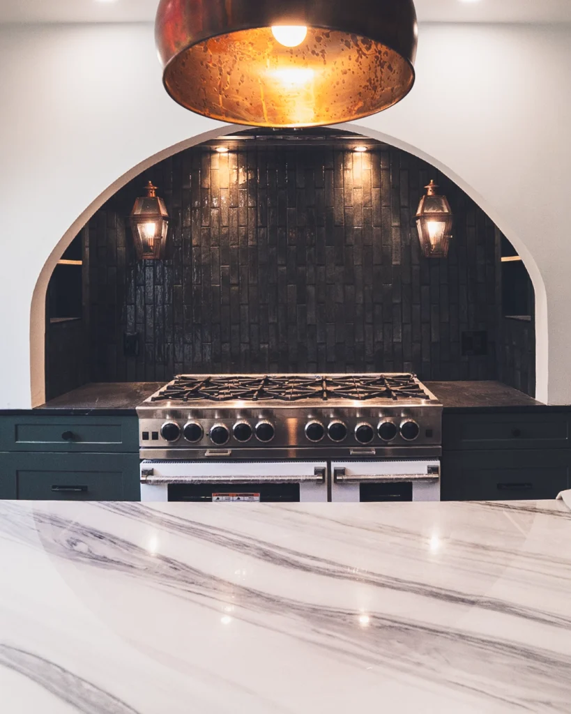 Kitchen with arched black tile range wall and marble island