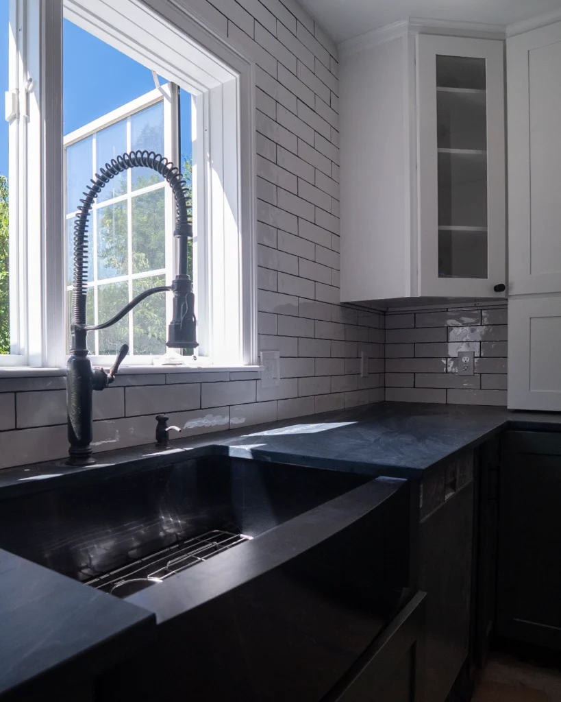 Black farmhouse sink with white subway tile backsplash